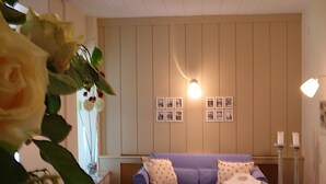 Una sala de estar con un sofá, una mesa y una pared decorada con marcos.