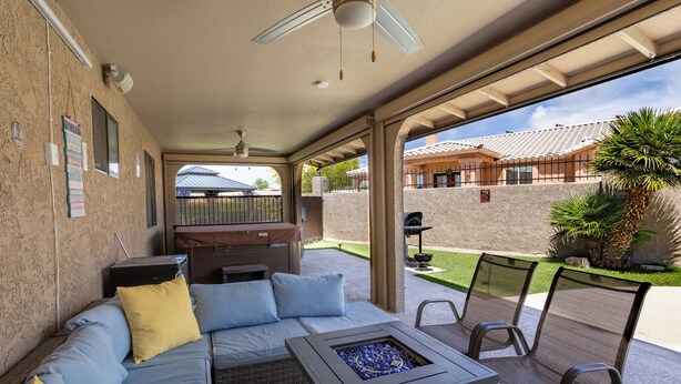 Patio esterno con divano, sedie, un braciere e vista su una casa.