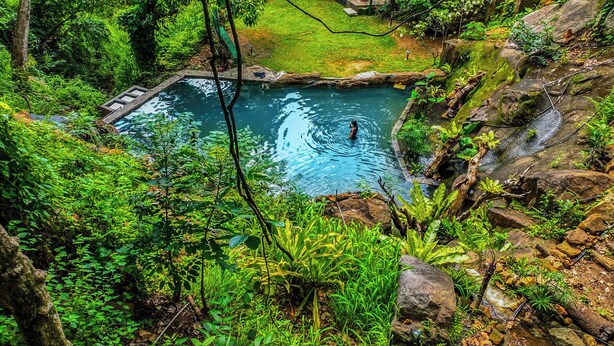 A natural pool surrounded by lush greenery and rocks. - Siyonra Bungalow  (Thotagamuwa)