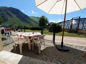 Relax in a shaded seating area with a table and chairs, surrounded by a mountainous landscape.