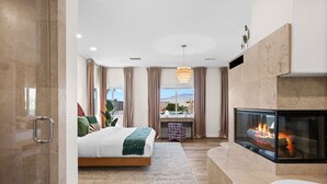 Un dormitorio moderno con una cama grande, chimenea y vistas al exterior.