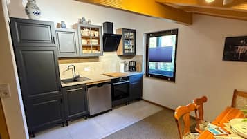 A compact kitchen with dark cabinets, a built-in oven, and a window providing natural light.