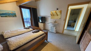 Une chambre avec deux lits, une télévision, un lavabo et un miroir.