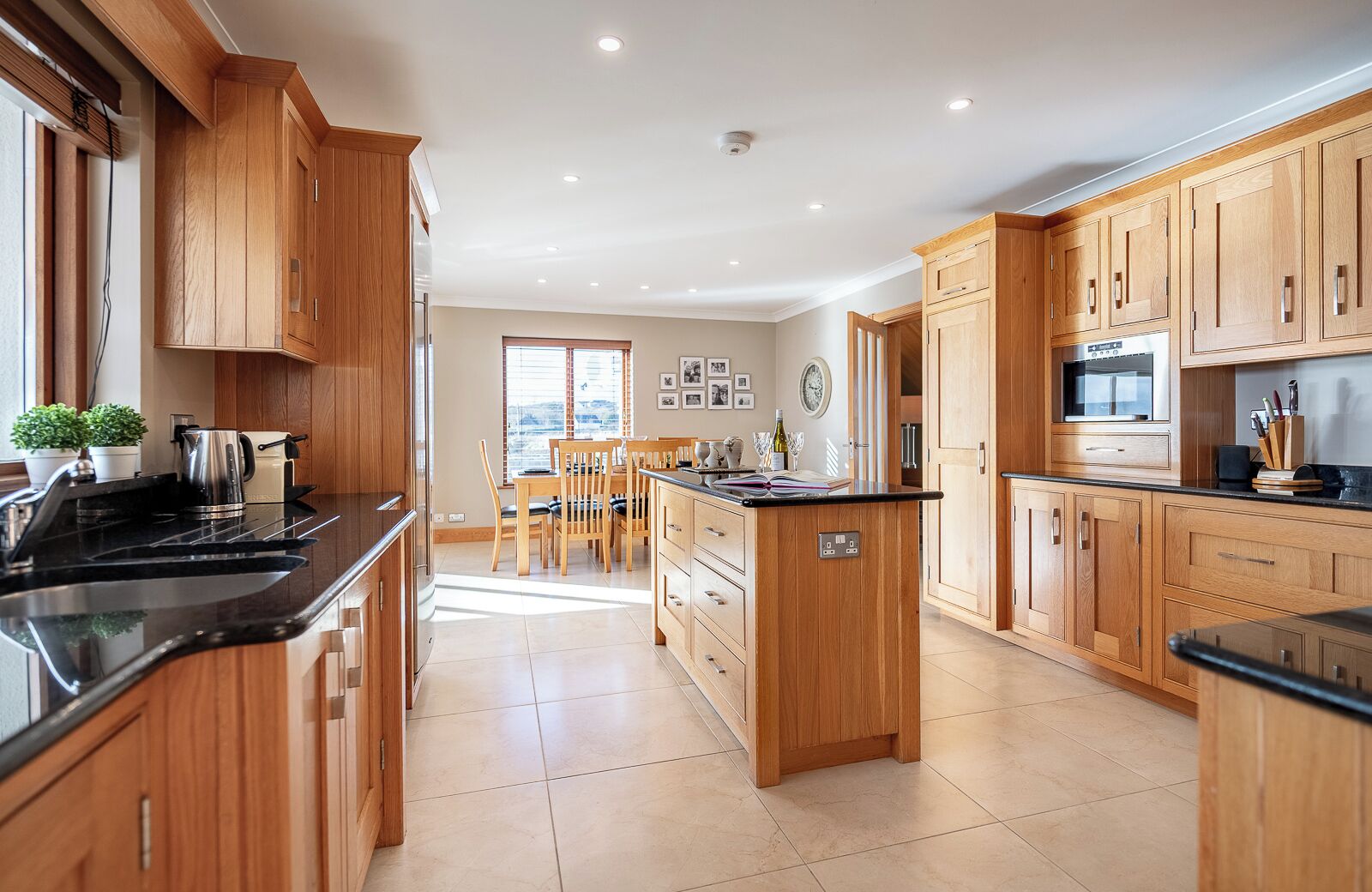 A spacious kitchen with wooden cabinets, a central island, and a dining area with a window view.