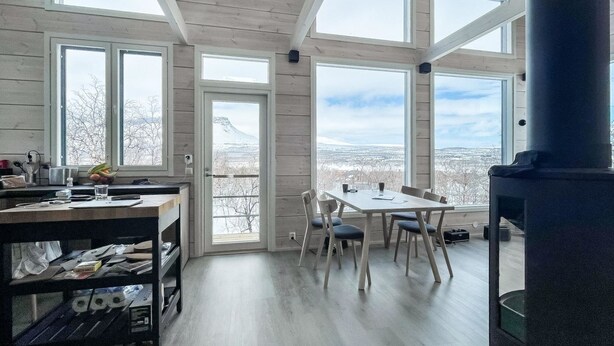 A spacious room with large windows, a wooden ceiling, and a fireplace.