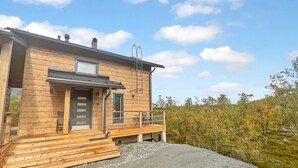 A wooden cabin with a front door, a small porch, and a chimney.