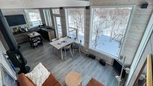 A modern interior with a dining area, kitchen, and large windows offering a view of a snowy landscape.