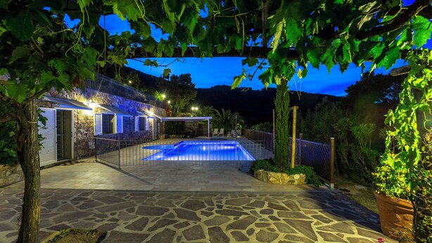 Un patio de piedra con piscina, zona cubierta y pared de piedra.