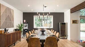 Une salle à manger moderne avec une table en bois foncé, dressée pour un repas, entourée de chaises marron.