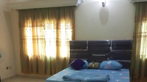 Ein Schlafzimmer mit Bett, Vorhängen, einem Ventilator und Fliesenboden.
