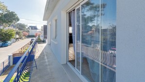 A balcony with a metal railing, a large sliding glass door, and a view of the street. - LA Baule, Duplex 4 Ch., Terrasse & Jardin à 5 mn de la Plage et des Commerces (La Baule-Escoublac)