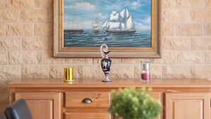 A dining area with a table set for four, a potted plant on the table, and a painting of a sailing ship on the wall. - LA Baule, Duplex 4 Ch., Terrasse & Jardin à 5 mn de la Plage et des Commerces (La Baule-Escoublac)