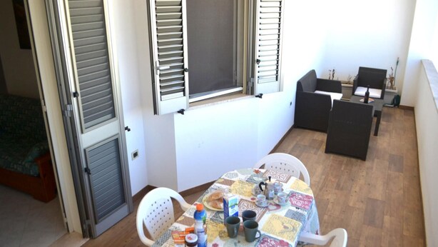 Ein kleiner Essbereich mit einem Tisch für zwei Personen, einem Stuhl und einem Fenster mit Fensterläden.