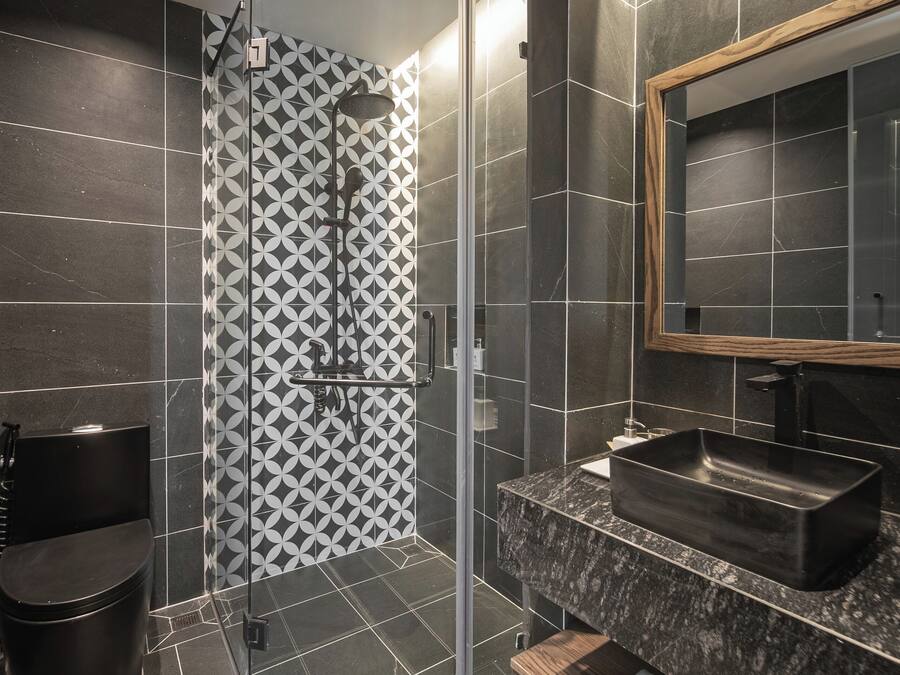 Een moderne badkamer met een douchecabine van glas, een zwart wastafelmeubel en een grote spiegel.