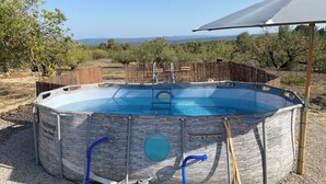 A round above-ground pool with a wooden deck, surrounded by a wooden fence, and an umbrella providing shade. - Casa the Dutchman,  totally off-grid,on a private plot of 10.000m2 (Navarres)