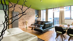 A modern living room with a sofa, a dining table, and a bed. - Exklusives City Apartment Nature (Leipzig)