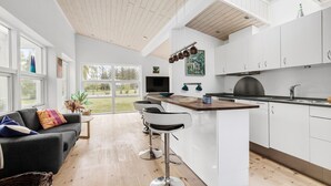 Une cuisine moderne avec des armoires blanches, un plan de travail en bois et une grande fenêtre.