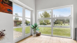 Une pièce spacieuse avec de grandes fenêtres, un plancher en bois et une plante en pot.