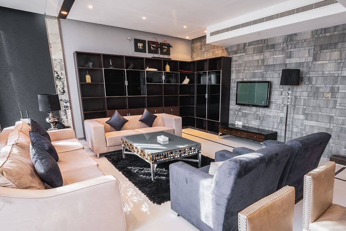A modern living room with a sofa set, a coffee table, and a TV mounted on the wall.