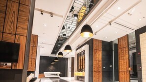 A modern hotel lobby with a reception desk, seating area, and a staircase. - Sway Suites (Manama)