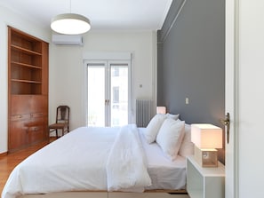 A bedroom with a large bed, a wooden wardrobe, a chair, and a radiator.