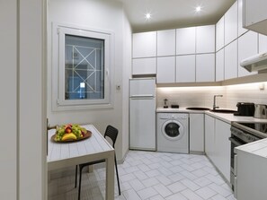 A compact kitchen with a washing machine, a sink, and a stove.