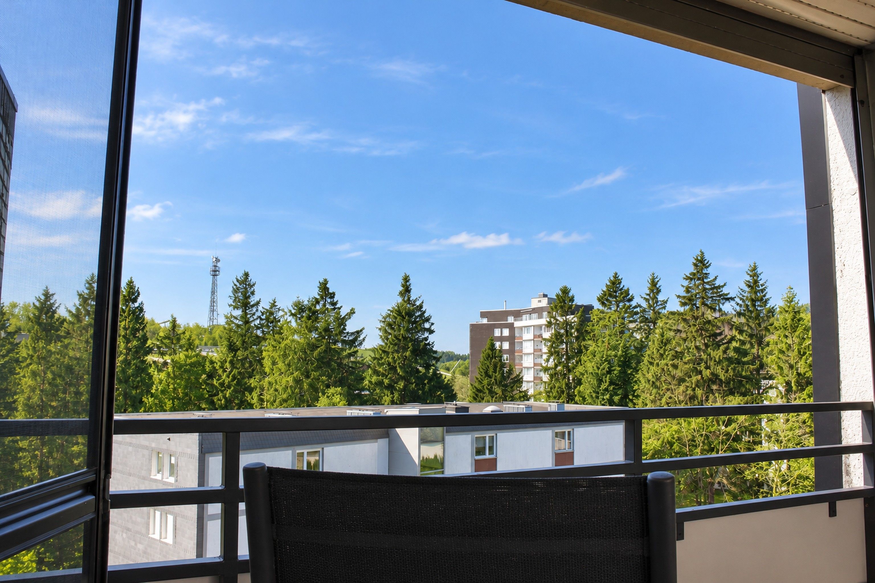 Ein Balkon mit Blick auf einen Wald und Gebäude.