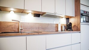 Eine moderne Küche mit weißen Schränken, einer Holz Arbeitsplatte, einem eingebauten Backofen und einer Kaffeemaschine.