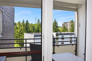 A balcony with a view of a building with a brick facade and a tree-lined street. - Schöne Ferienwohnung mit Balkon Direkt am Erlebinsberg Kappe (Winterberg)