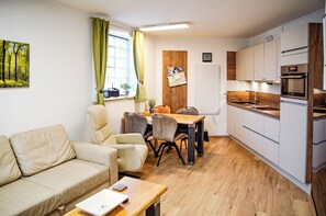 Cozy living space with a kitchenette, sofa, and dining table near a window.