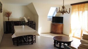 A dining area with a table and chairs, a television on a cabinet, and a chandelier. - Maison Située Dans le Vignoble, Appartement à L'étage Avec Entrée Indépendante (Soultzmatt)