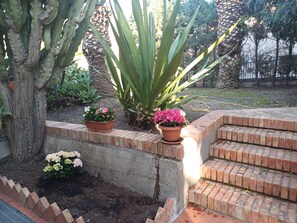 A garden with a concrete wall, brick steps, and potted plants. - Villa entirely surrounded by garden a stone's throw from the sea. (Brancaleone Marina)