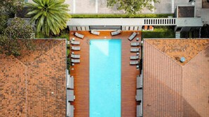 An aerial view of a rooftop swimming pool with a wooden deck, surrounded by lounge chairs and a palm tree. - MOT Rentals + Madero Azopardo 'C' Lux 1 Bd (Puerto Madero)