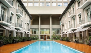 Ein modernes Hotel mit einem zentralen Pool, mehreren Balkonen und Außenbereichen zum Sitzen.