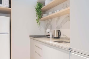 Eine moderne Küche mit weißen Schränken, einer Granitarbeitsplatte, einer Kaffeemaschine und einem Spülbecken.