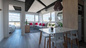 Una sala de estar moderna con comedor, ventanas amplias y vista a la ciudad.