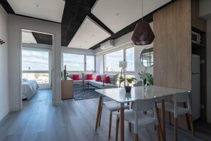 Ein modernes Wohnzimmer mit Essbereich, großen Fenstern und Blick auf die Stadt.