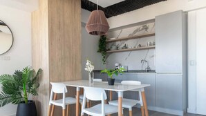 Una cocina moderna con armarios blancos, salpicadero de mármol y una lámpara colgante.