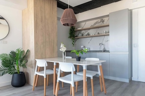 A modern kitchen with white cabinets, a marble backsplash, and a hanging pendant light. - MOT Rentals + Madero Azopardo 'D' Lux 1 Bd (Puerto Madero)