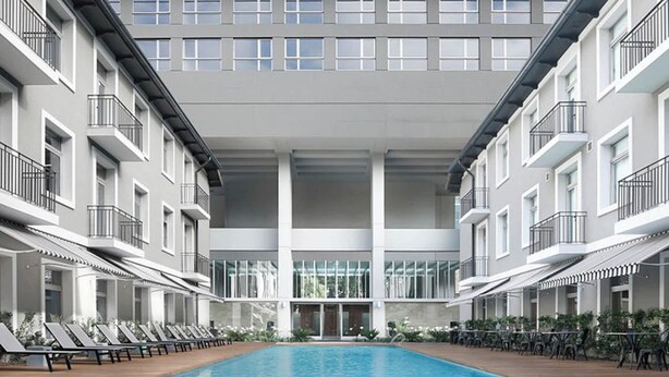Un hotel moderno con piscina central, múltiples balcones y un diseño limpio y contemporáneo.