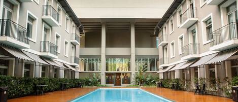Un hotel con piscina central, varios balcones y un diseño arquitectónico moderno.