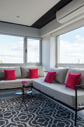 A modern living room with a sofa, a small table, and a patterned rug. - MOT Rentals + Madero Azopardo 'D' Lux 1 Bd (Puerto Madero)