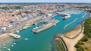 An aerial view of a coastal town with a marina, residential buildings, and a railway line.