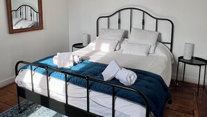A neatly made bed with white and blue bedding, a black metal frame, and a blue patterned rug. There are three framed artworks on the wall above the bed. - Maison POL Amboise (Amboise)