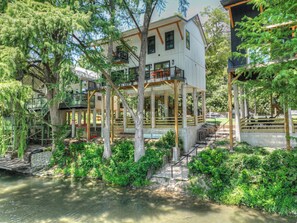 Stunning building with balconies and outdoor terraces overlooking lush surroundings and a body of water.