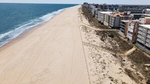 Un hotel frente a la playa con una playa de arena, vista al océano y varias edificaciones con balcones.