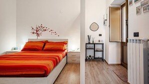A modern bedroom with a large bed, a nightstand, a small table with decorative items, and a radiator. - Casa Don Raffaele (Agira)