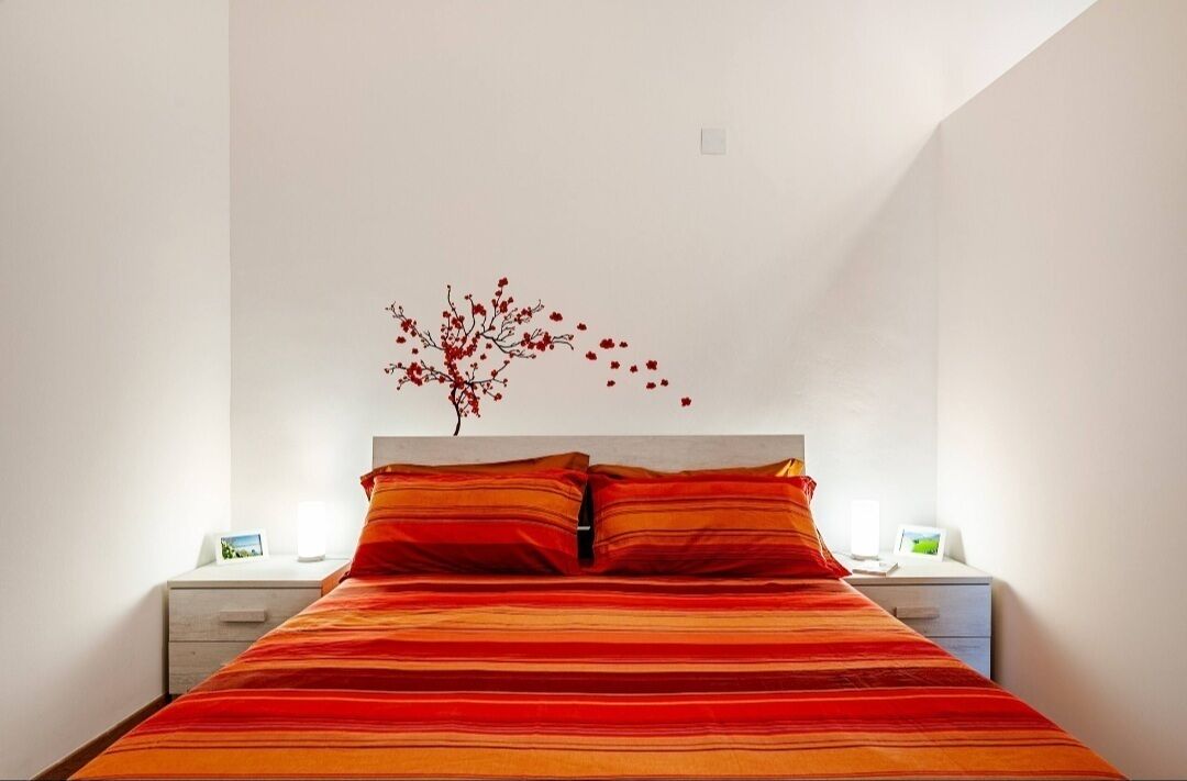 Un dormitorio con una cama, dos mesitas de noche y un adorno en la pared.