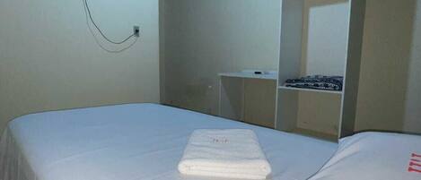 A bedroom with a bed, a TV mounted on the wall, and a wardrobe.