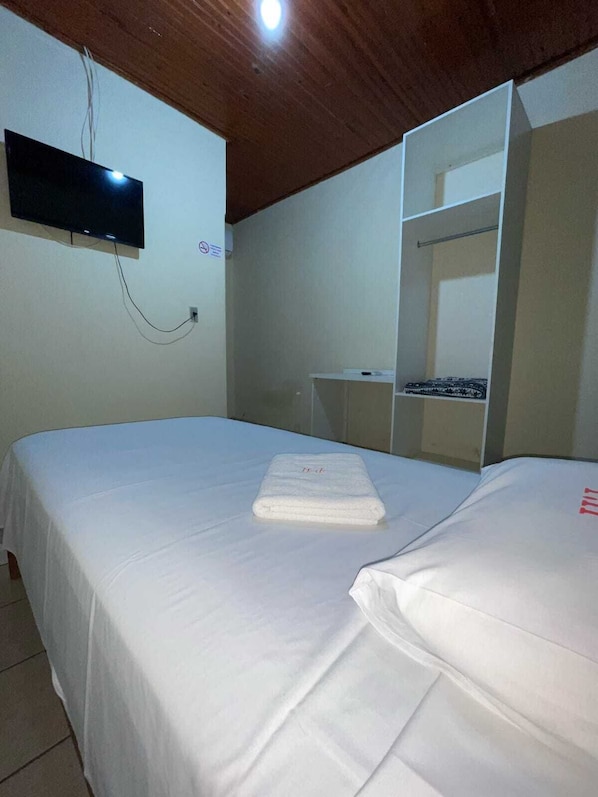 A bedroom with a bed, a TV mounted on the wall, and a wardrobe. - Plaza Hotel Jataí (Jatai)
